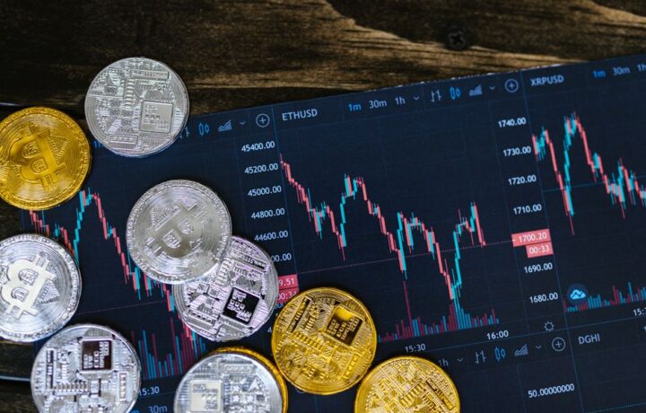 Close-up of gold and silver cryptocurrency coins on a digital trading chart.