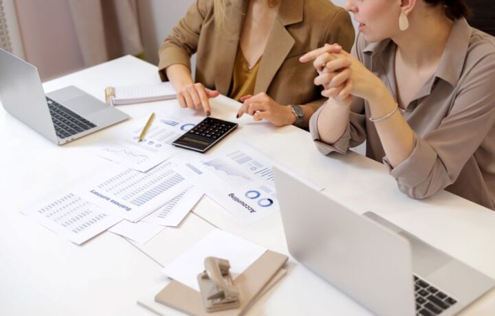 Two professionals collaborating on financial documents in a modern office setting.