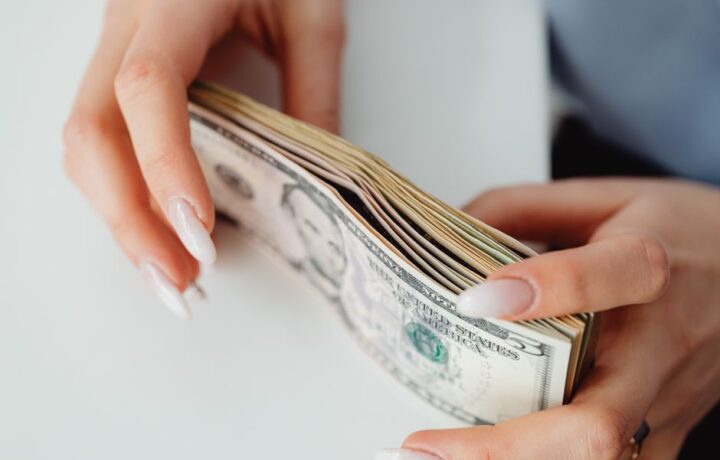 Hands carefully holding a stack of US dollar bills, representing finance and currency.