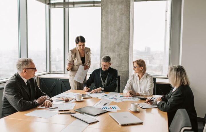 Professionals discussing documents during a business meeting in a modern office setting.