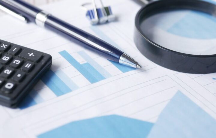 Close-up of calculator, pen, and magnifying glass on financial documents.
