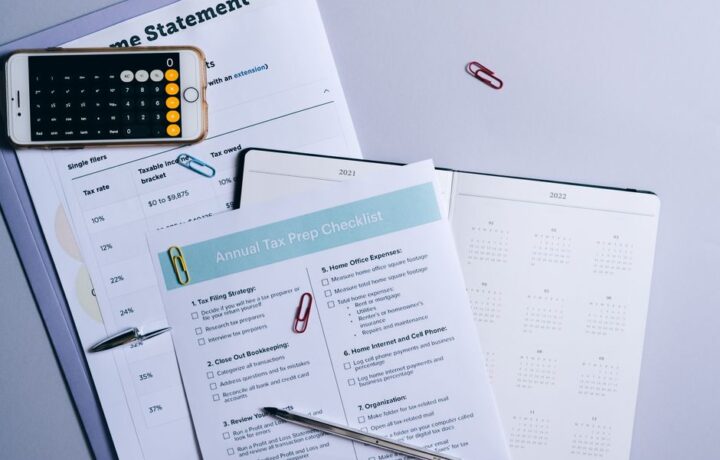 Flat lay of a tax preparation checklist, calculator, and financial documents on a desk.