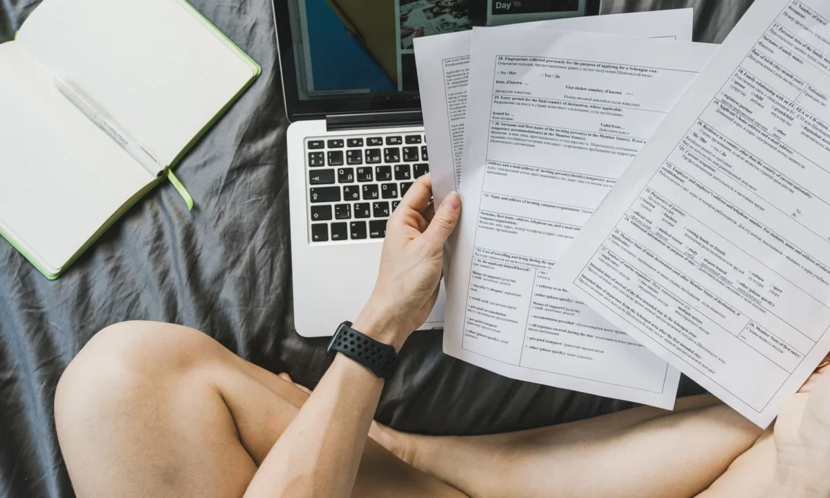 Freelancer organizando documentos em um laptop em casa, representando o controle financeiro para autônomos