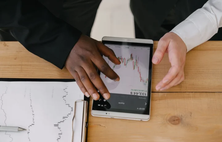 Profissionais analisando tendências do mercado financeiro em um tablet, representando o uso de software financeiro