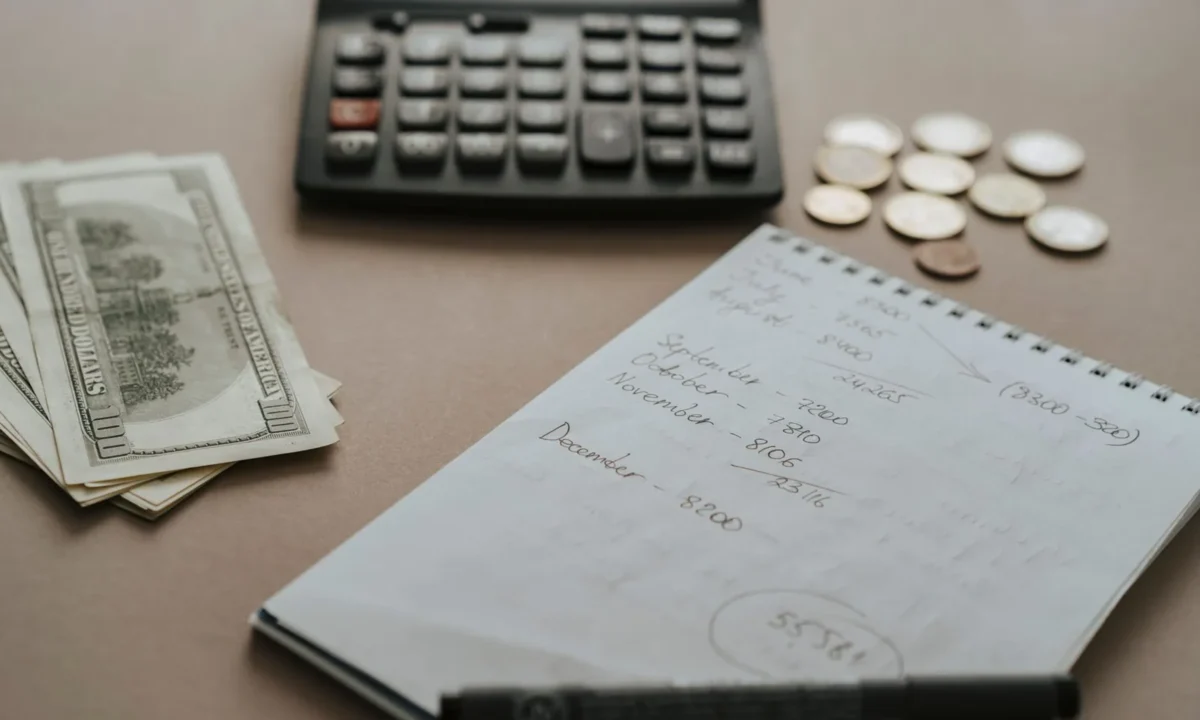 Ambiente de trabalho com calculadora, dinheiro e notas financeiras, ilustrando a gestão de despesas