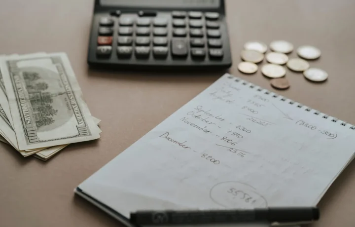 Ambiente de trabalho com calculadora, dinheiro e notas financeiras, ilustrando a gestão de despesas