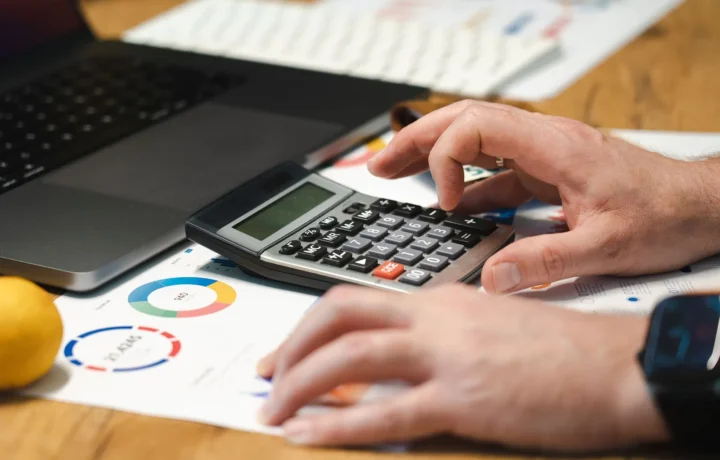 Empreendedor comparando o melhor sistema financeiro para MEI no notebook com calculadora na mesa