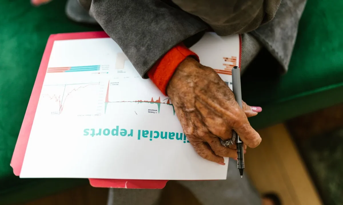 Mulher idosa segurando caneta sobre relatório financeiro em close