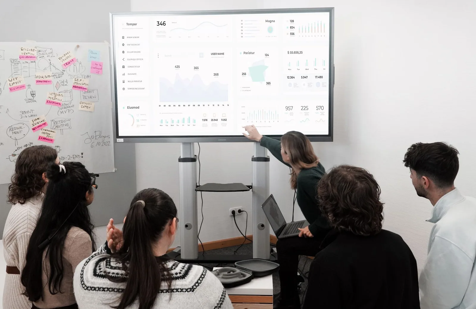Profissionais acompanham apresentação corporativa com gráficos na tela durante reunião de equipe